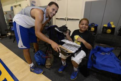 Taliq Davis, a ten year old boy with an inoperable brain tumor, shows off the athletic shoes given to him by Golden State Warriors' Stephen Curry during a meeting at the Golden State Warriors Training Facility. 