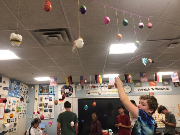 Junior Harry Beyer helps classmates in German II hang painted eggs that student made the week of April 22, during the longer block schedule.