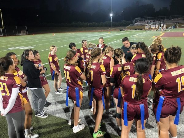 Flag football players huddle around Coach Lauren Lahey enroute to a 19-0 win over Berean High School Sept. 27. The team would go on to win the DAL  in the first year of the sport.